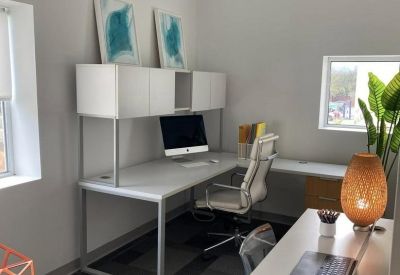 L-shaped white desk setup with a computer and decorative teal artwork.