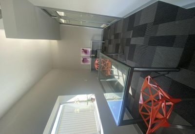 Modern meeting room with a glass table and geometric orange chairs.