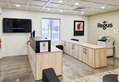 Reception area featuring a light wood service desk, a wall-mounted TV, and company branding.