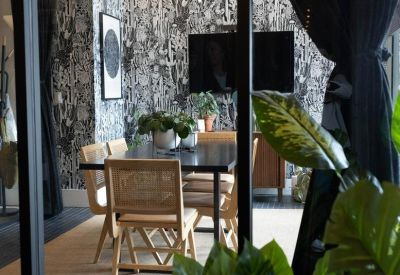 Stylish dining area with black and white patterned wallpaper and light wood chairs.