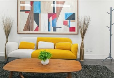 Vibrant lounge area with a yellow and white sofa, wooden coffee table, and abstract art.
