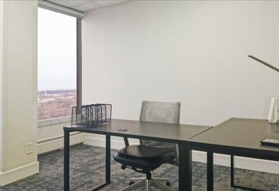 Private office suite with a dark wood desk and large window showing city views.
