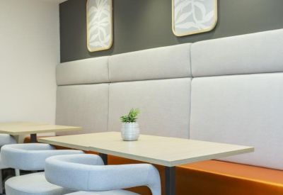 Dining area featuring a long cushioned bench, light wood tables, and modern artwork.