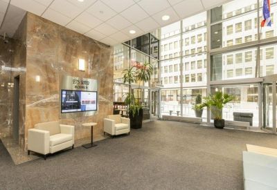 Large lobby with marble walls, white armchairs, and floor-to-ceiling windows.