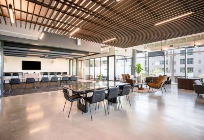 Spacious open-plan lounge and coworking area with wooden slat ceilings and marble tables.