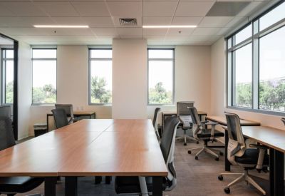 Bright internal office suite with wooden desks and ergonomic mesh chairs.