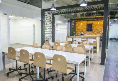 Spacious communal dining area with long white tables, light wood chairs, and a vibrant yellow feature wall.