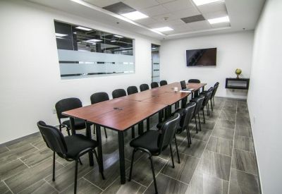 Professional conference room with a long wooden table and black cushioned chairs.