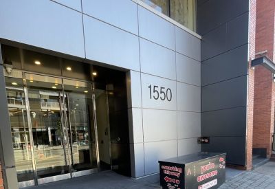Modern glass entrance with 1550 building numbering and a branded welcome box.
