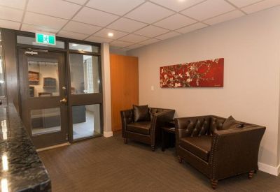 Lounge area with tufted leather armchairs and a red floral painting.