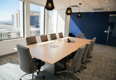 Spacious boardroom with a light wood table, grey chairs, and a deep blue feature wall.