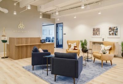 Modern reception area with a slatted wood desk, blue armchairs, and branded signage.