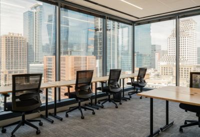 Window-side workstations with ergonomic chairs and views of downtown skyscrapers.