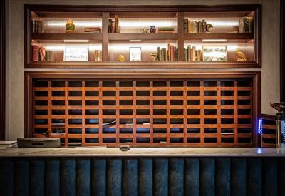 Branded reception desk with a wooden lattice front and backlit shelving for books.