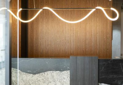 Open lobby area with a plush lounge chair and view into a glass-walled office.