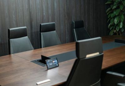 Sleek modern boardroom with a dark wood table and high-back leather chairs.