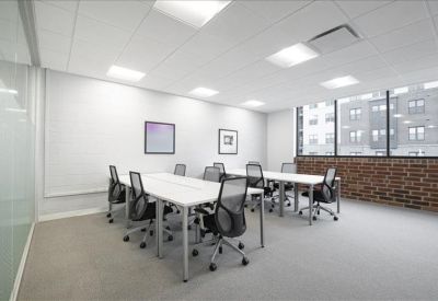 Bright open-plan workspace with multiple white desks and black mesh chairs.