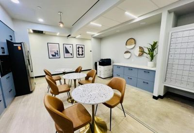 Communal kitchen area with marble café tables, tan chairs, and blue cabinetry.