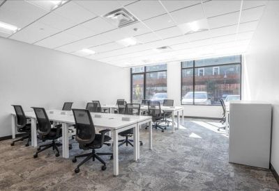 Spacious open-plan workspace with multiple desks and large windows.
