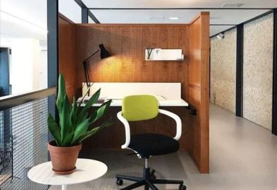 Wood-paneled individual workstation with a green chair and potted plant.