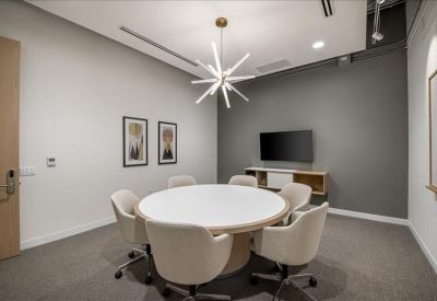 Modern conference room with a round white table and a starburst light fixture.