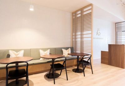 Reception area with a warm wooden desk, branded logo wall, and cozy banquette seating.