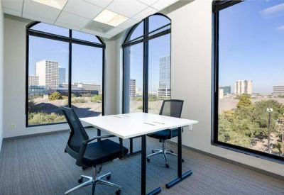 Small private office with two desks and large arched windows overlooking the city.