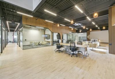 Expansive open-plan office area with long communal desks and warm lighting.