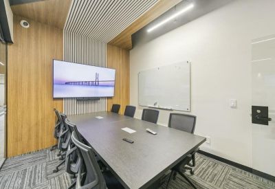 Meeting room with a large screen, white board, and sleek wood accents.