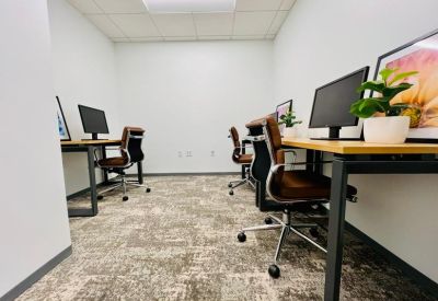 Symmetrical four-person office suite with light wood desks and ergonomic chairs.