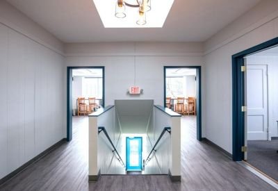 Hallway view showing a staircase and entrances to bright office suites.