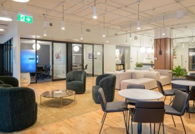 Reception lounge with green armchairs, a marble coffee table, and soft beige sofas.