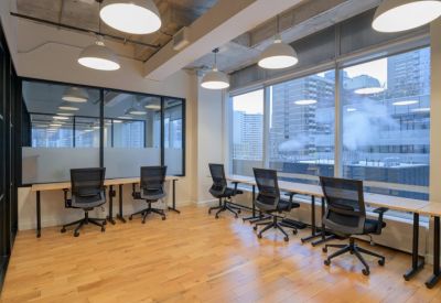 Bright workspace with rows of desks, ergonomic chairs, and large windows overlooking the city.