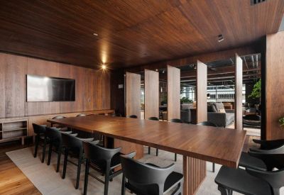 Meeting room with a long wooden table and black chairs.