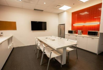 Modern office kitchen and dining area featuring a vibrant orange feature wall.