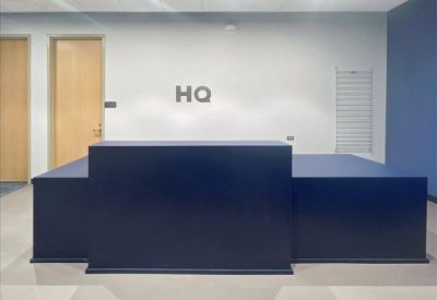 Minimalist reception area with a dark navy desk and 'HQ' signage on the wall.