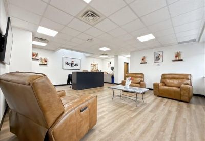Spacious lounge area featuring tan leather armchairs and a black reception desk.