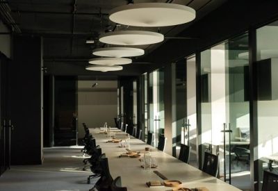 Long white communal work table under large circular pendant lights.