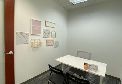 Small meeting room with a white table, black chairs, and decorative wall art.