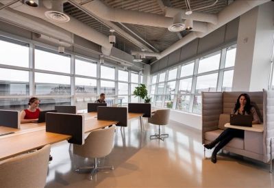 Spacious communal workspace with modular desks and a high-backed privacy sofa.