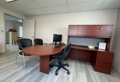 Corner office workstation with an L-shaped desk and overhead storage.