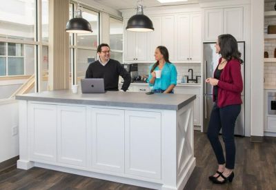 Bright kitchen island with people talking and a laptop.
