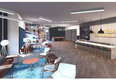 Spacious coworking lounge with diverse seating, a colorful rug, and a long breakfast bar.