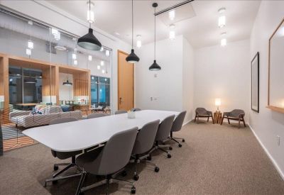 Conference room with a long white table, grey chairs, and modern pendant lighting.