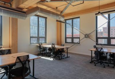 Open-plan office space with height-adjustable desks and ergonomic mesh chairs.