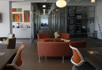 Spacious communal lounge with orange sofas, modern armchairs, and colorful abstract wall art.