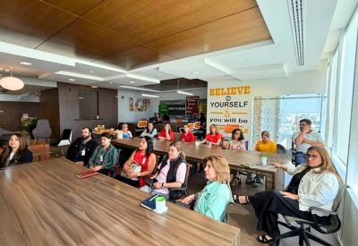 Large group of people attending a presentation in a modern conference room with wood-paneled ceilings.