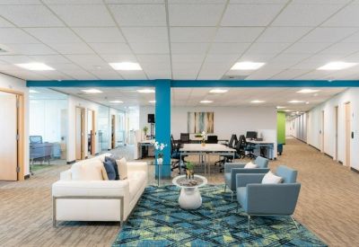 Open-plan coworking space with a blue accent pillar and comfortable white and blue seating.