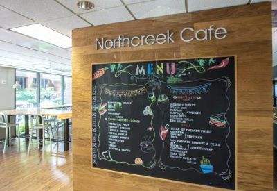 Building cafe with a chalkboard menu, wood-paneled walls, and high-top seating.