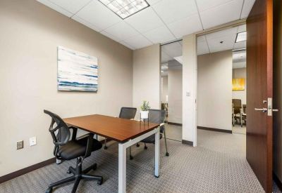 Private three-person office with a wooden desk and modern ergonomic chairs.